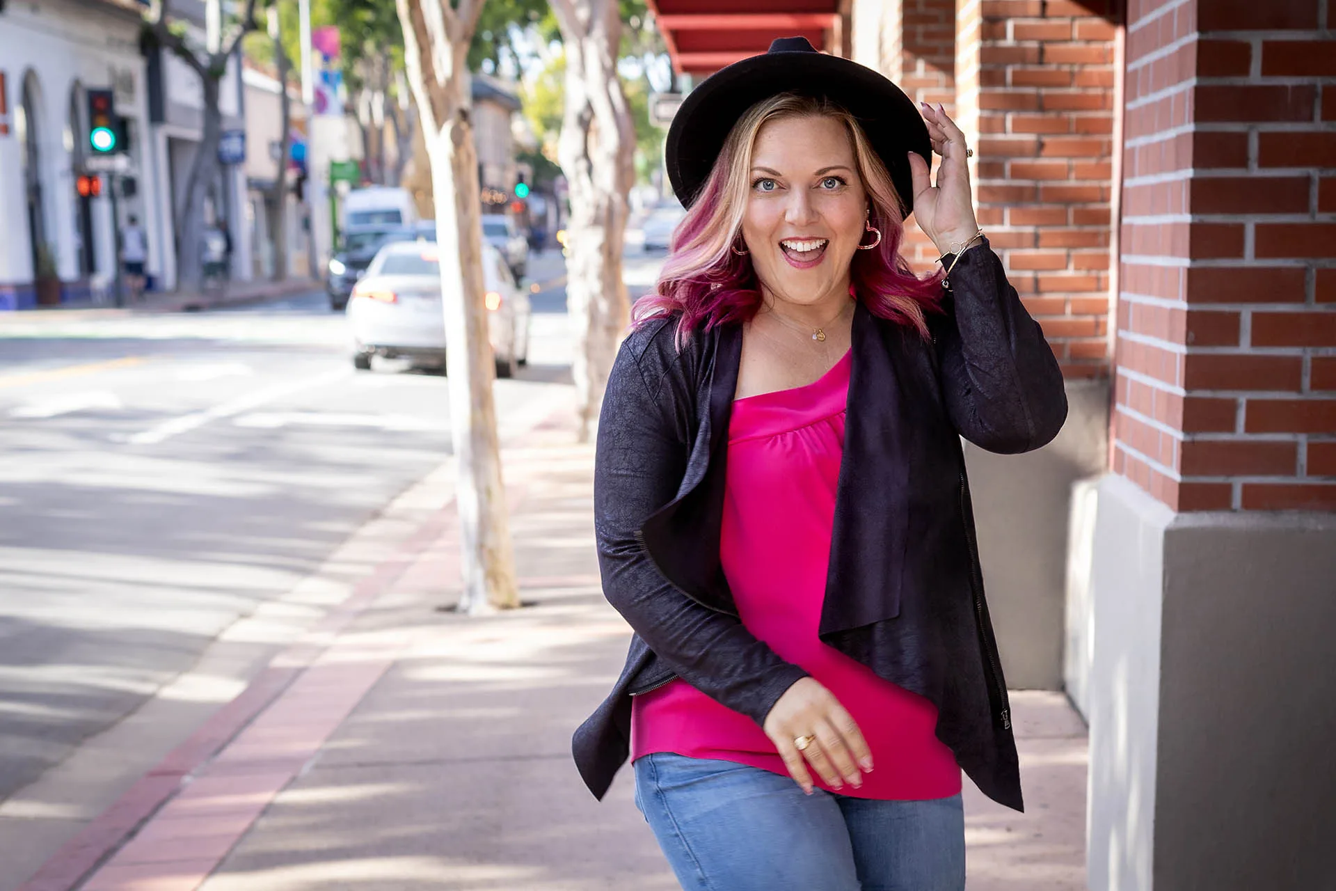 Woman in pink walking and laughing on the street.