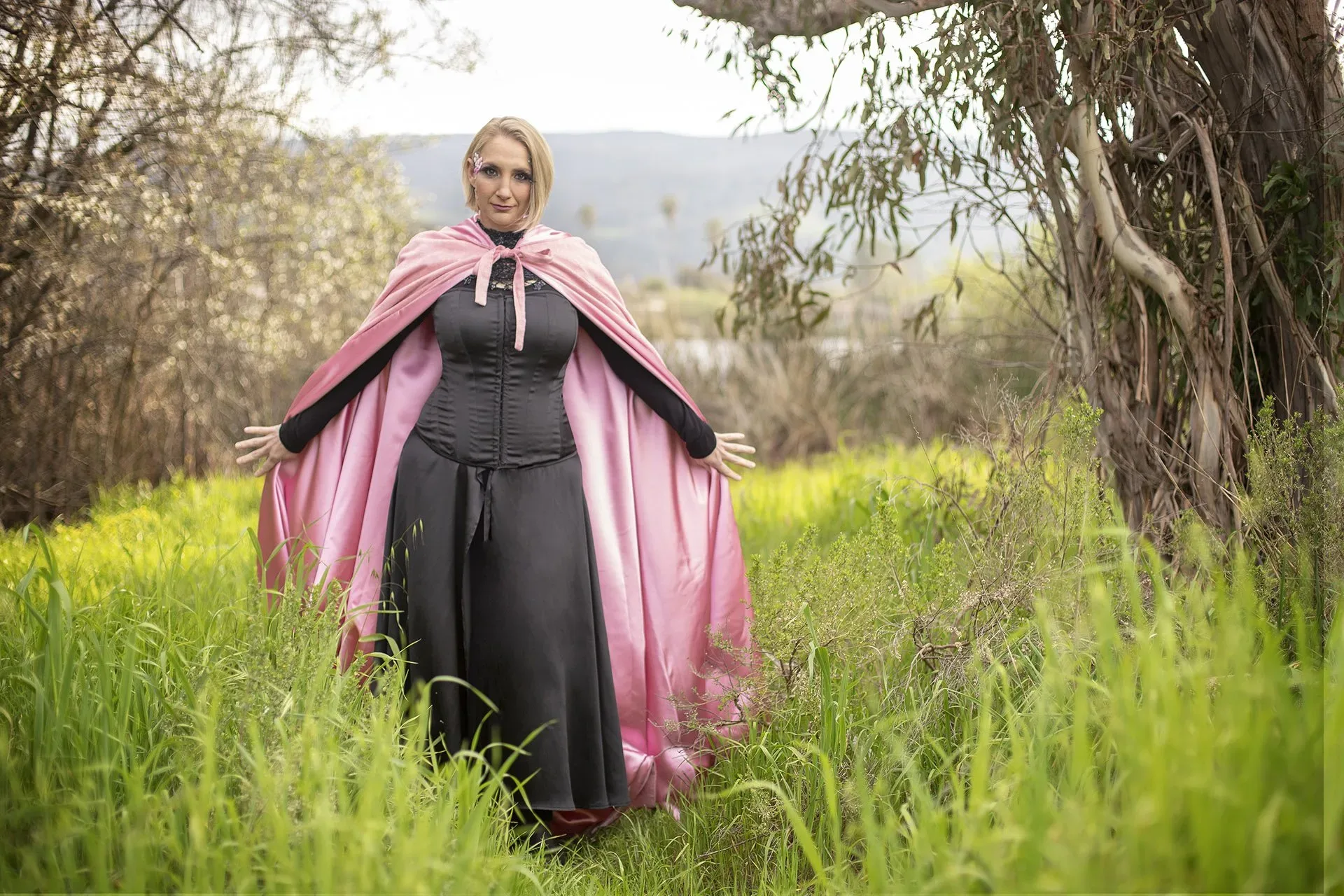A Woman's Power in a black dress and pink cloak on her journey.